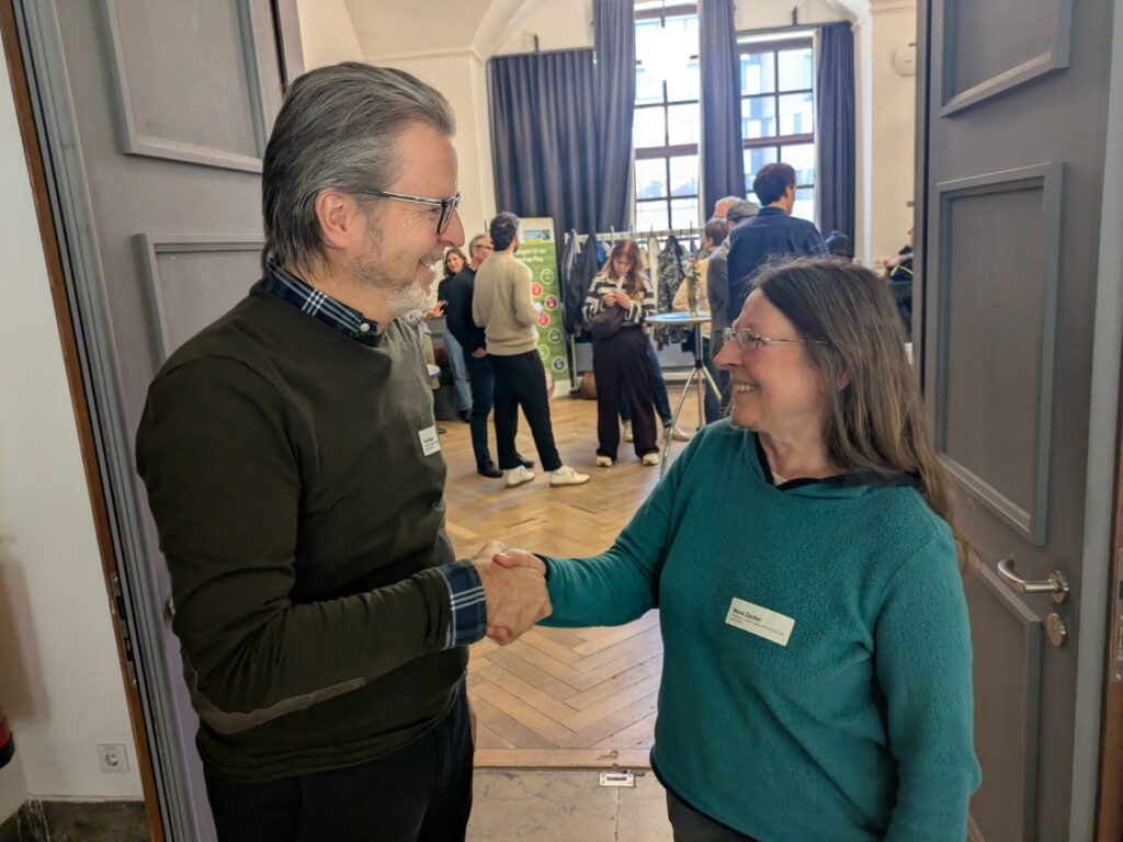 Ralf Mützel und Maria Zeußel begrüßen sich bei der Fair-Trade-Werkstatt in Nürnberg.